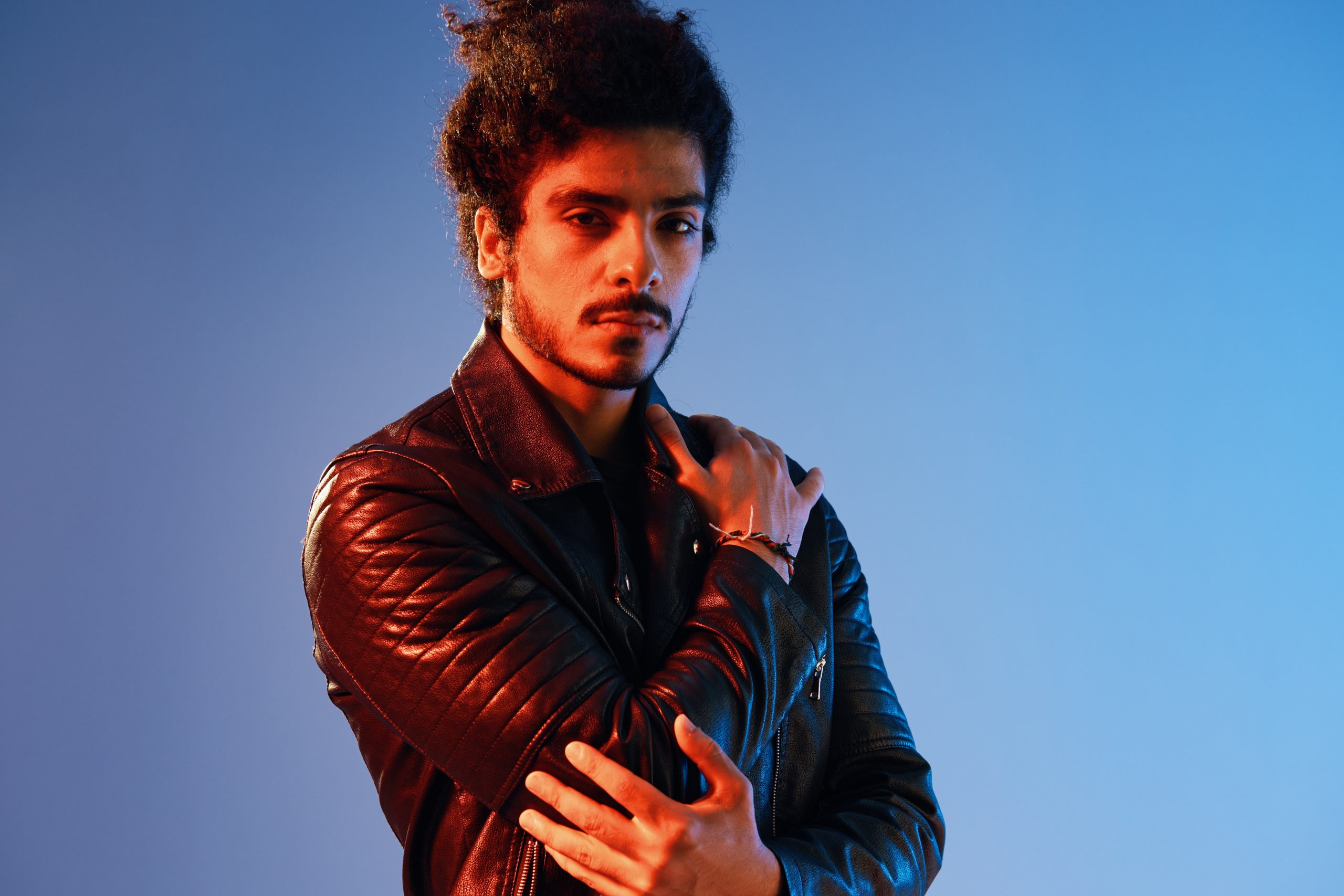 portrait-of-a-stylish-man-with-curly-hair-on-a-blu-2026-03-20-06-08-05-utc